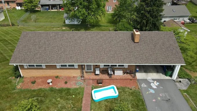Brick ranch home with a new shingle roof beside a pool