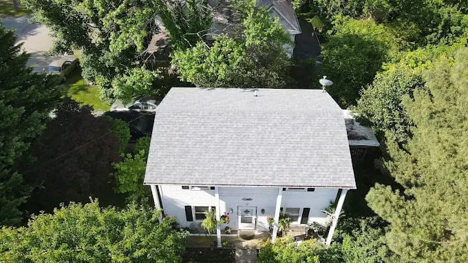 Aerial view of a white house with a new shingle roof