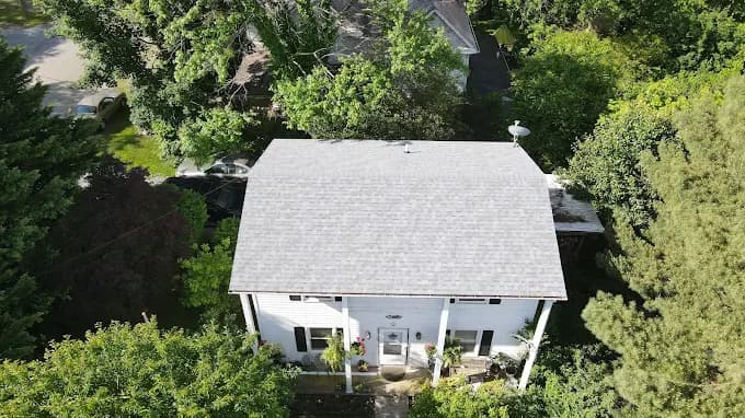 Aerial view of a white house with a new shingle roof